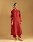 A close-up of a women's maroon Pakistani kurta showing the fabric texture and band collar neckline.