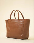 Brown croc-embossed tote bag with double top handles and a structured silhouette on a neutral background
