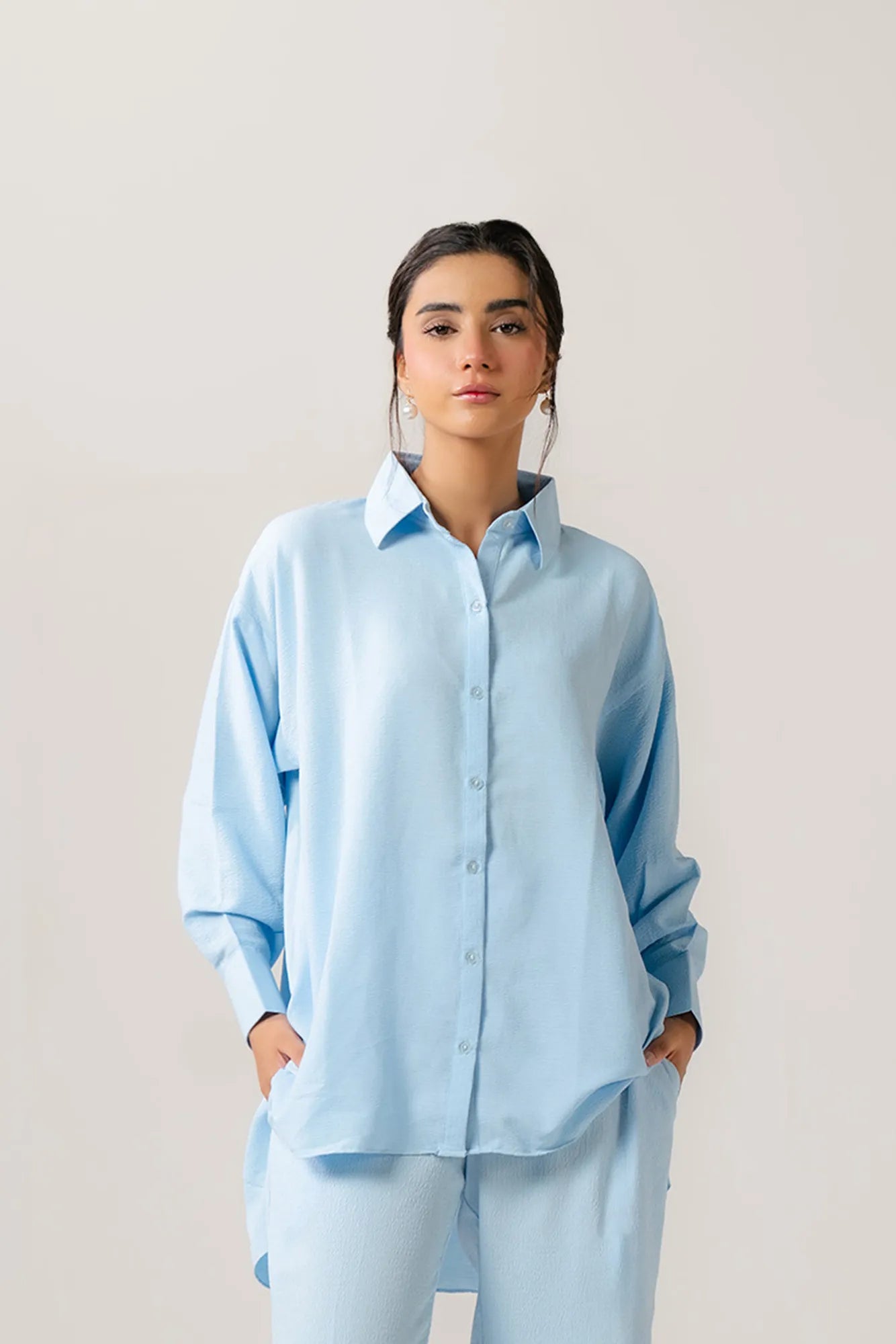 Casual everyday style with a relaxed-fit light blue ladies poplin shirt, unbuttoned over a white cami for effortless layering