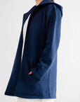 Chic navy blue cardigan with functional hood and pockets, styled for a minimalist look with white attire.