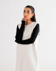 Chic white maxi dress styled with black long sleeves and boots, perfect for a contemporary casual outfit.