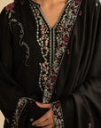 Close-up of black embroidered linen suit neckline featuring pastel threadwork detailing