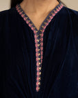Close-up of embroidered V-neck panel on deep blue velvet fabric.