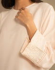 Close-up of neckline and upper front of peach embroidered kurta with soft drape.