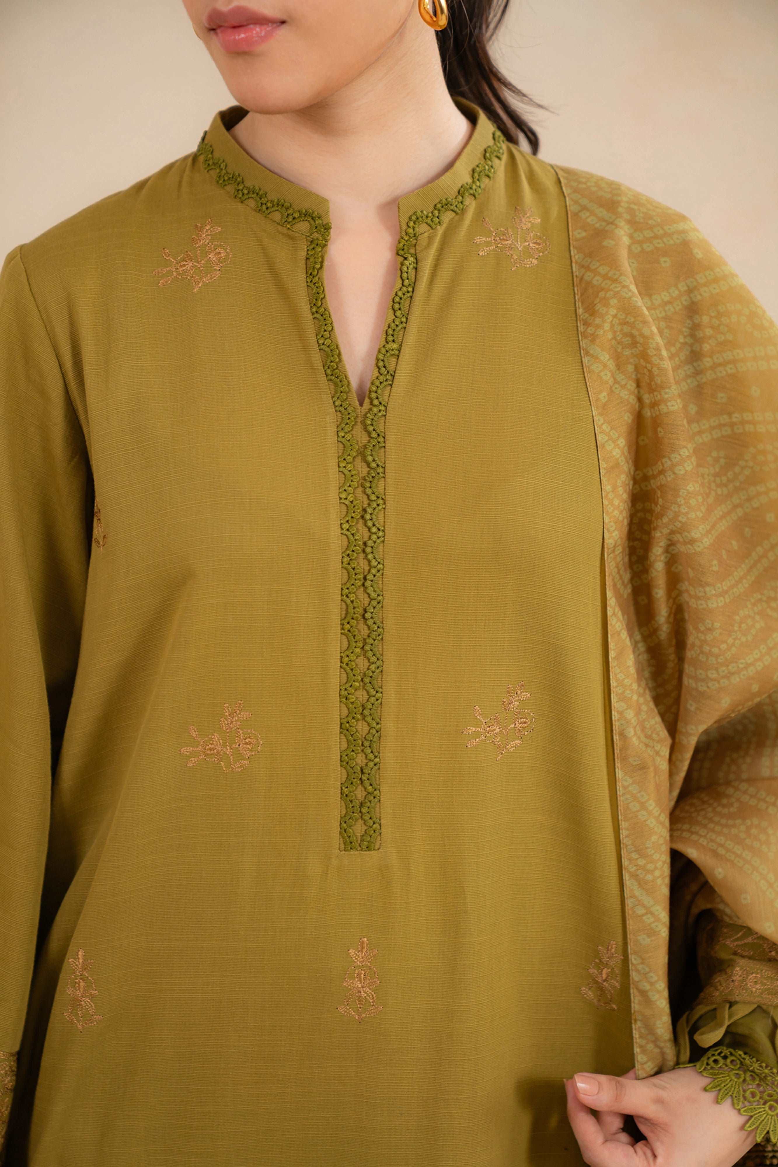 Close-up of olive green embroidered fabric with lace trim