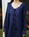 A woman wearing a navy blue embroidered tunic with a matching draped shawl, featuring floral embroidery and a scalloped neckline, photographed outdoors.