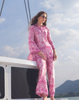 Full-length view of woman wearing a pink printed silk co-ord set on a yacht