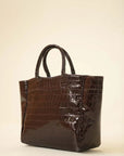 Glossy brown crocodile-embossed tote bag with double top handles, shown in a clean studio setting.