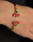 Hand wearing a gold-tone lotus kundan cuff bangle with pink floral motifs