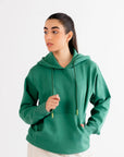 Model wearing a classic green hoodie with a front pouch and drawstring hood, showcasing a cozy wardrobe essential.