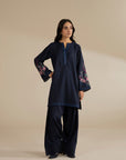 Model wearing navy blue 2 piece embroidered suit with floral sleeves, full front view in studio.