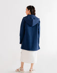 Navy blue hooded cardigan with front pockets, perfect for layering, worn by a model in a white dress.