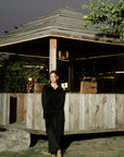 Outdoor full-length view of black velvet co-ord set near wooden structure, showing overall silhouette.