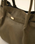 Side angle of olive green suede-look tote bag featuring minimal front strap detail and roomy shape.