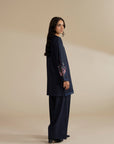 Side pose of model in navy blue 2 piece embroidered suit, showing drape and fit.