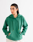 Woman wearing a basic green hoodie with adjustable drawstrings and a front pocket, perfect for casual wear.