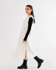 Woman wearing a white maxi dress with black long sleeves, styled with black ankle boots for a modern look