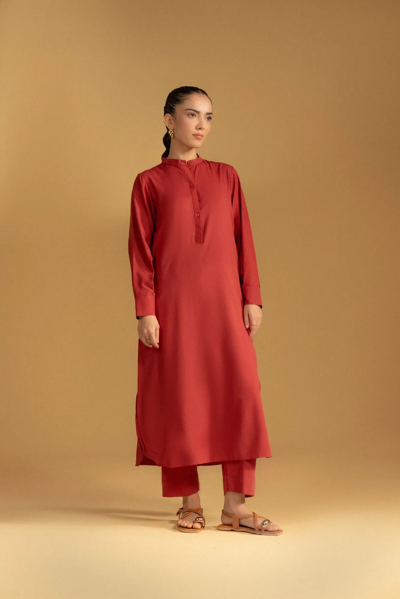A close-up of a women's maroon Pakistani kurta showing the fabric texture and band collar neckline.