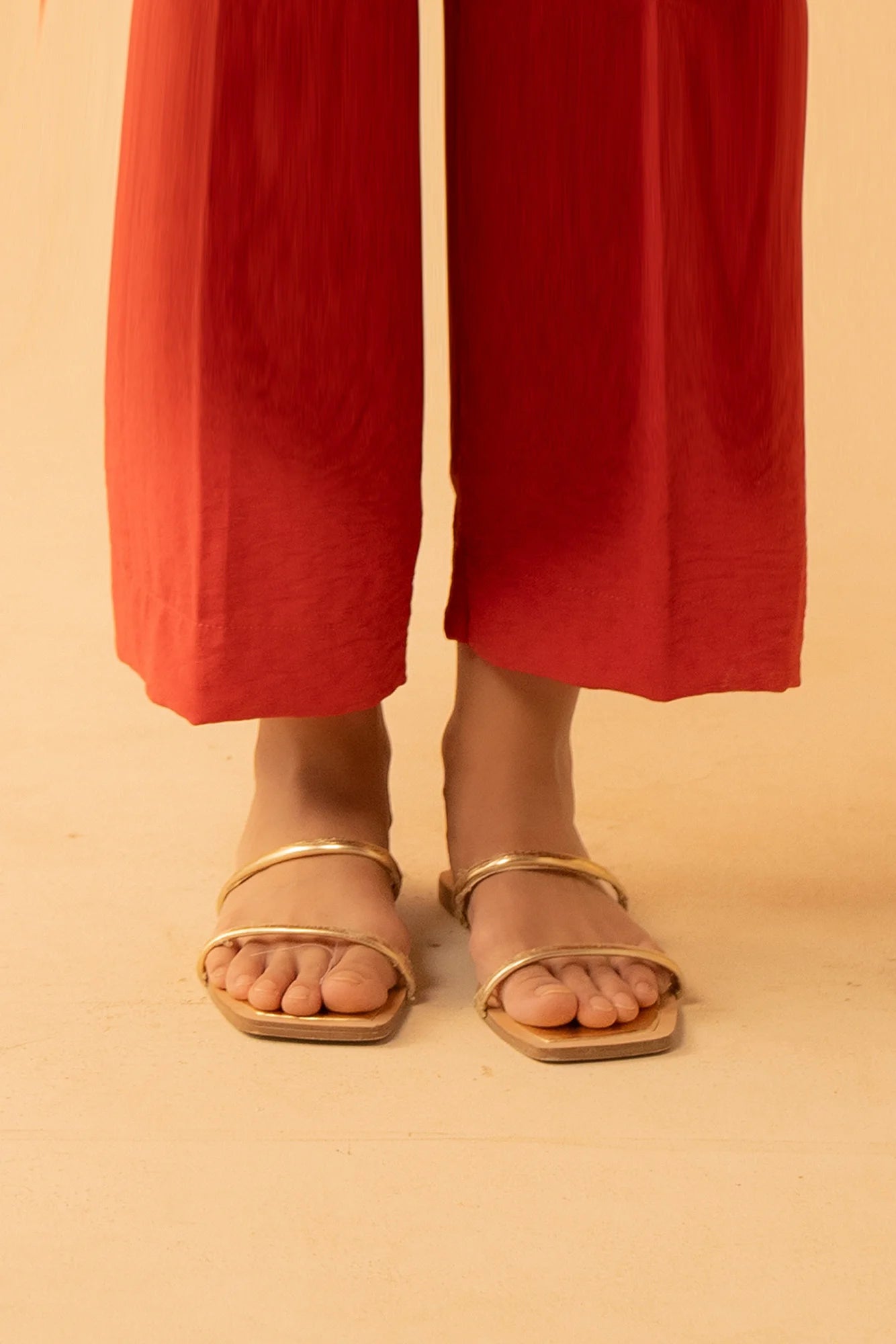 A full-length shot of a woman wearing Beyond East&#39;s red straight-fit trousers from the 2025 collection.