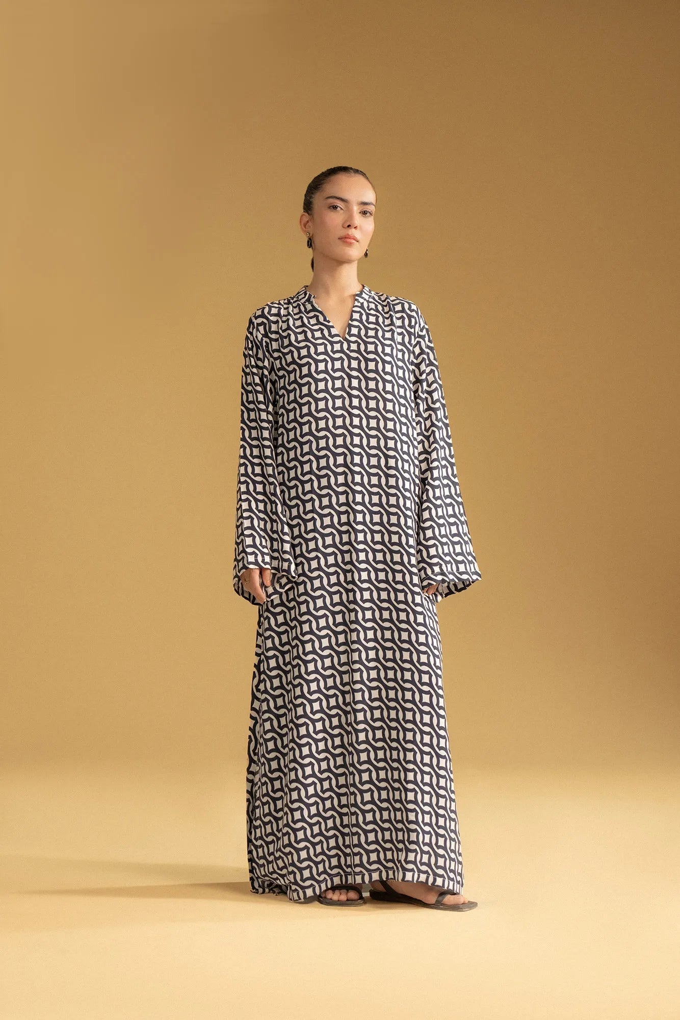 A woman wearing a stylish geometric-print kaftan, a popular long dress in Pakistani fashion.