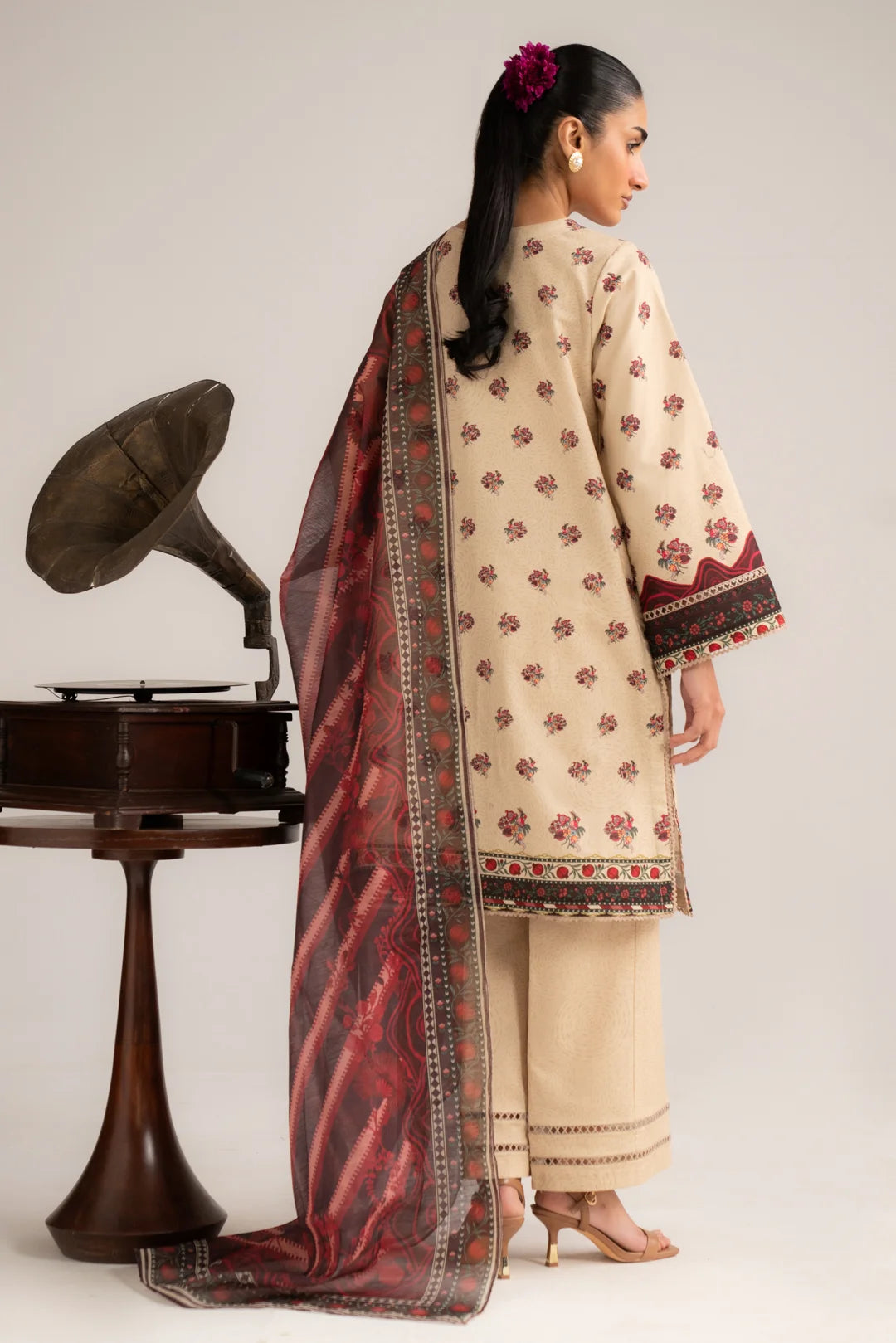 Angled pose of women’s ivory unstitched 3 piece lawn suit with traditional print