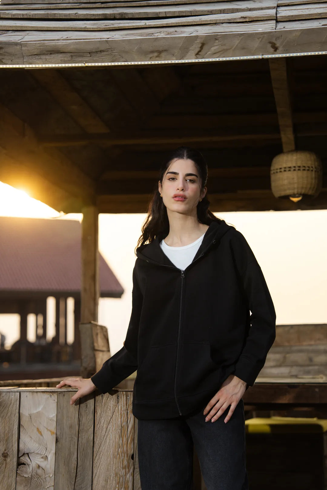 Black zipper hoodie styled open over white top, casual look