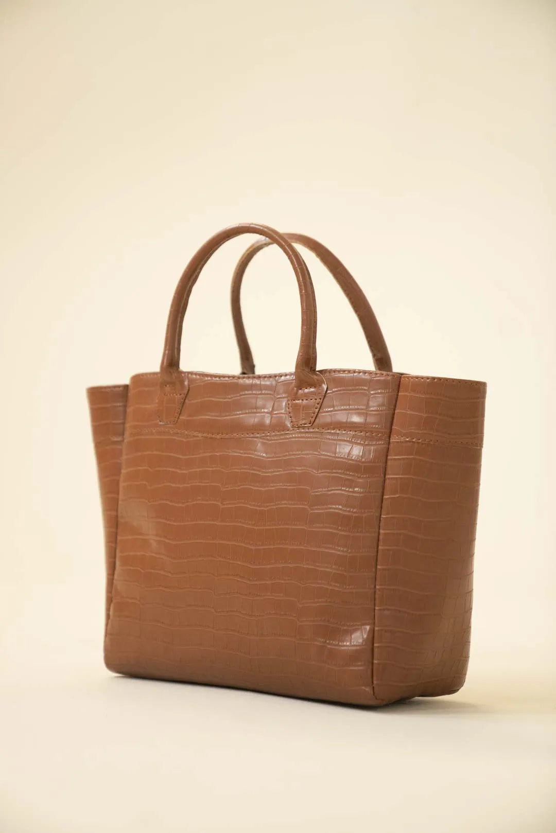 Brown croc-embossed tote bag with double top handles and a structured silhouette on a neutral background