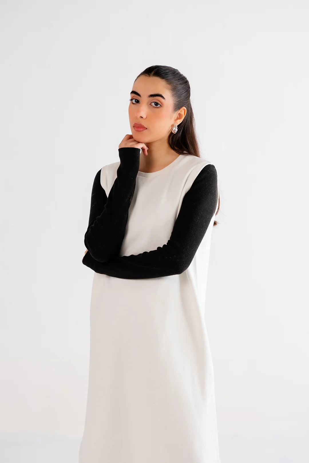 Chic white maxi dress styled with black long sleeves and boots, perfect for a contemporary casual outfit.