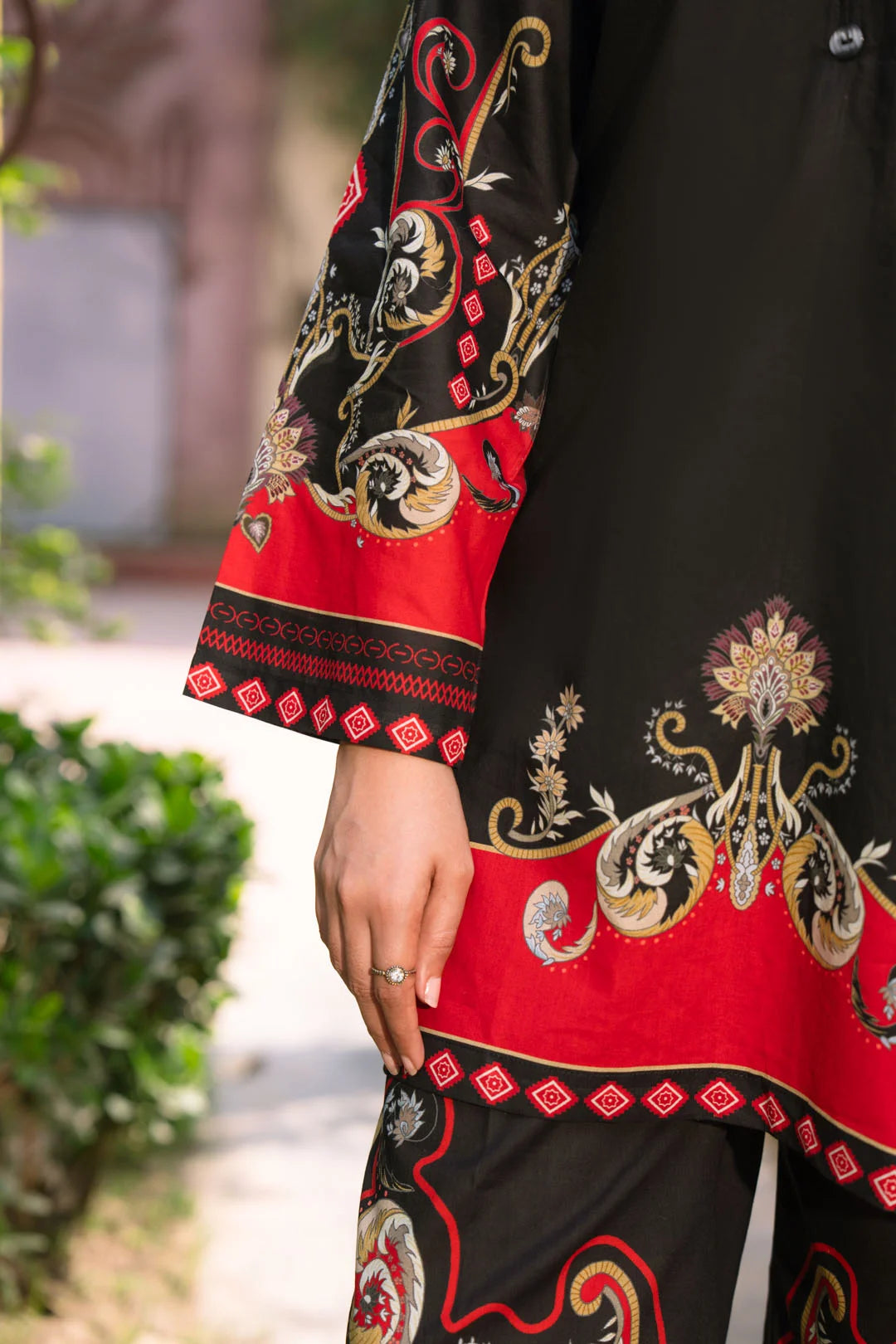 Close-up detail of black and red printed cambric sleeve and trouser design