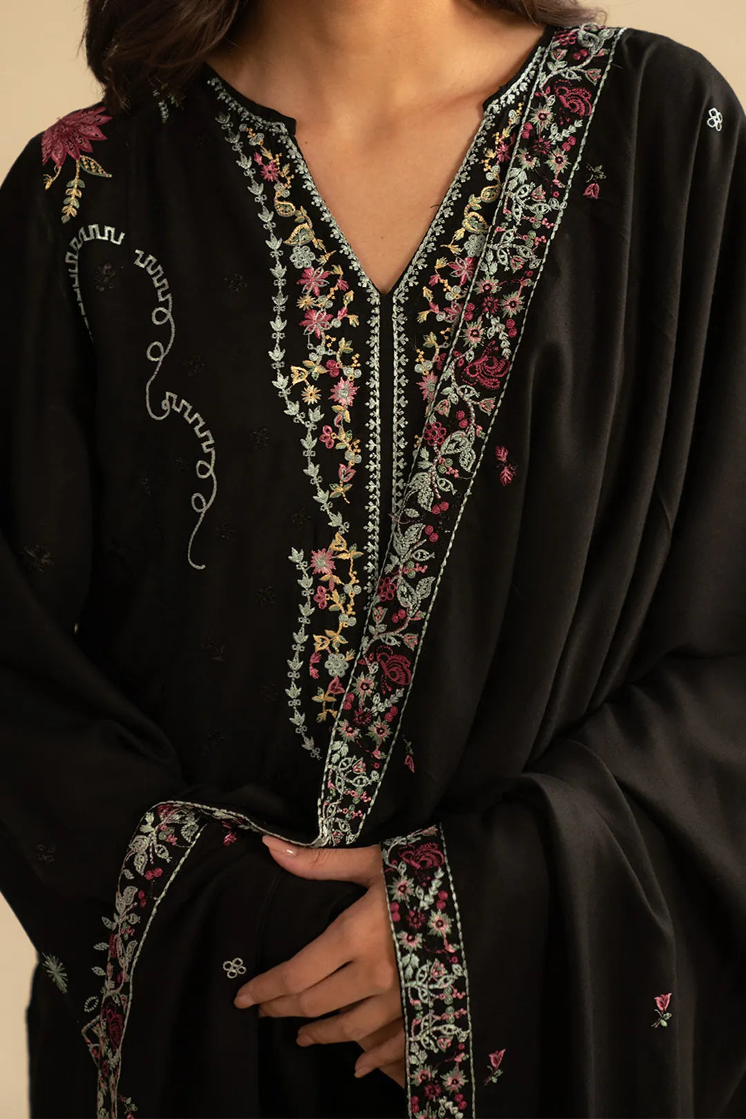 Close-up of black embroidered linen suit neckline featuring pastel threadwork detailing