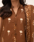 Close-up of brown printed linen shirt showing neckline and motif detail