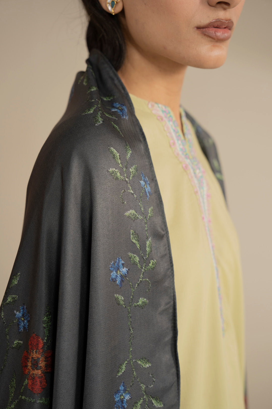 Close-up of dark green dupatta fabric showing print motifs and edging detail on the shoulder.