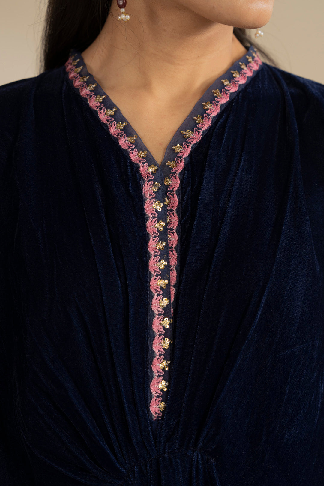Close-up of embroidered V-neck panel on deep blue velvet fabric.