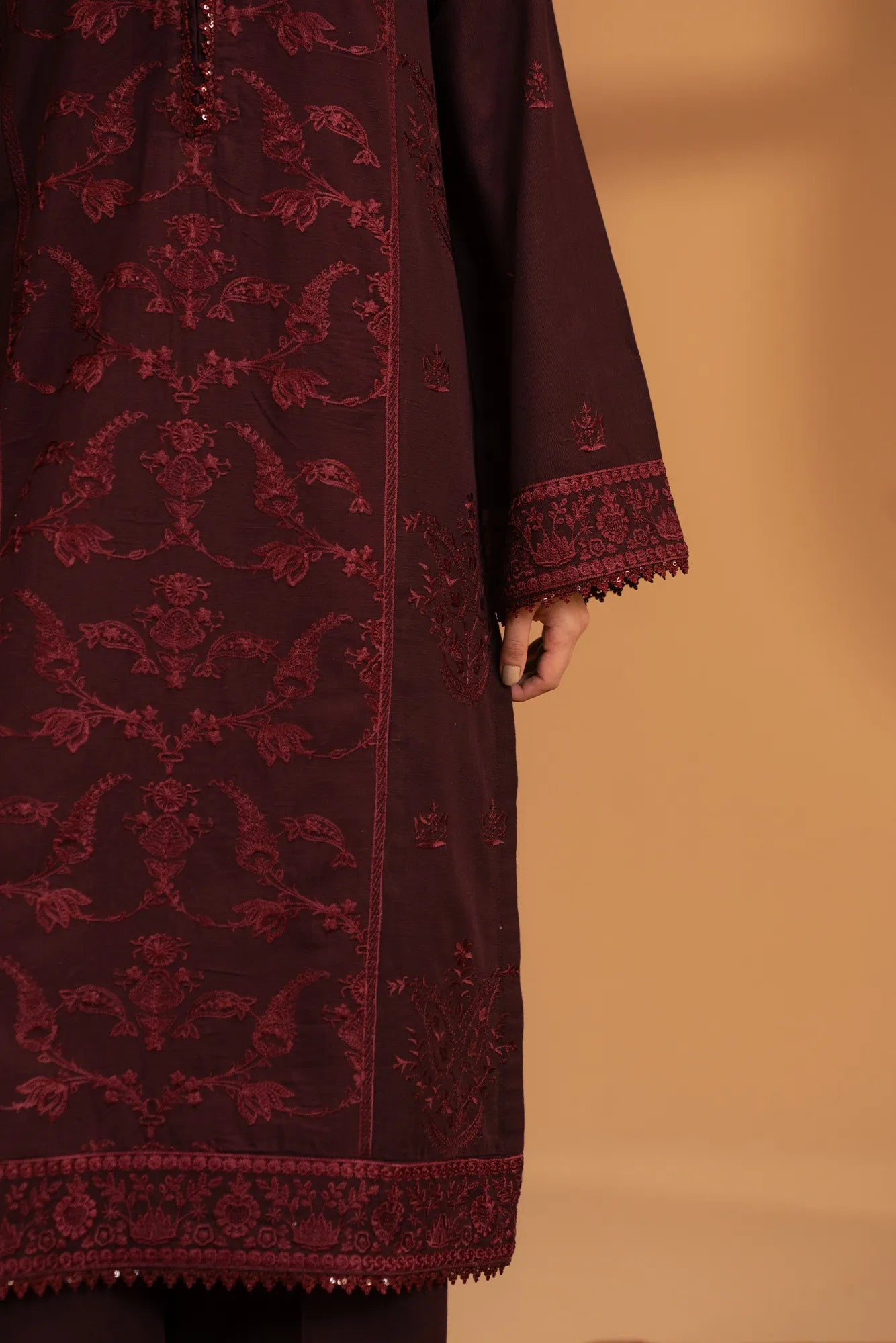 Close-up of embroidery pattern on maroon khaddar fabric