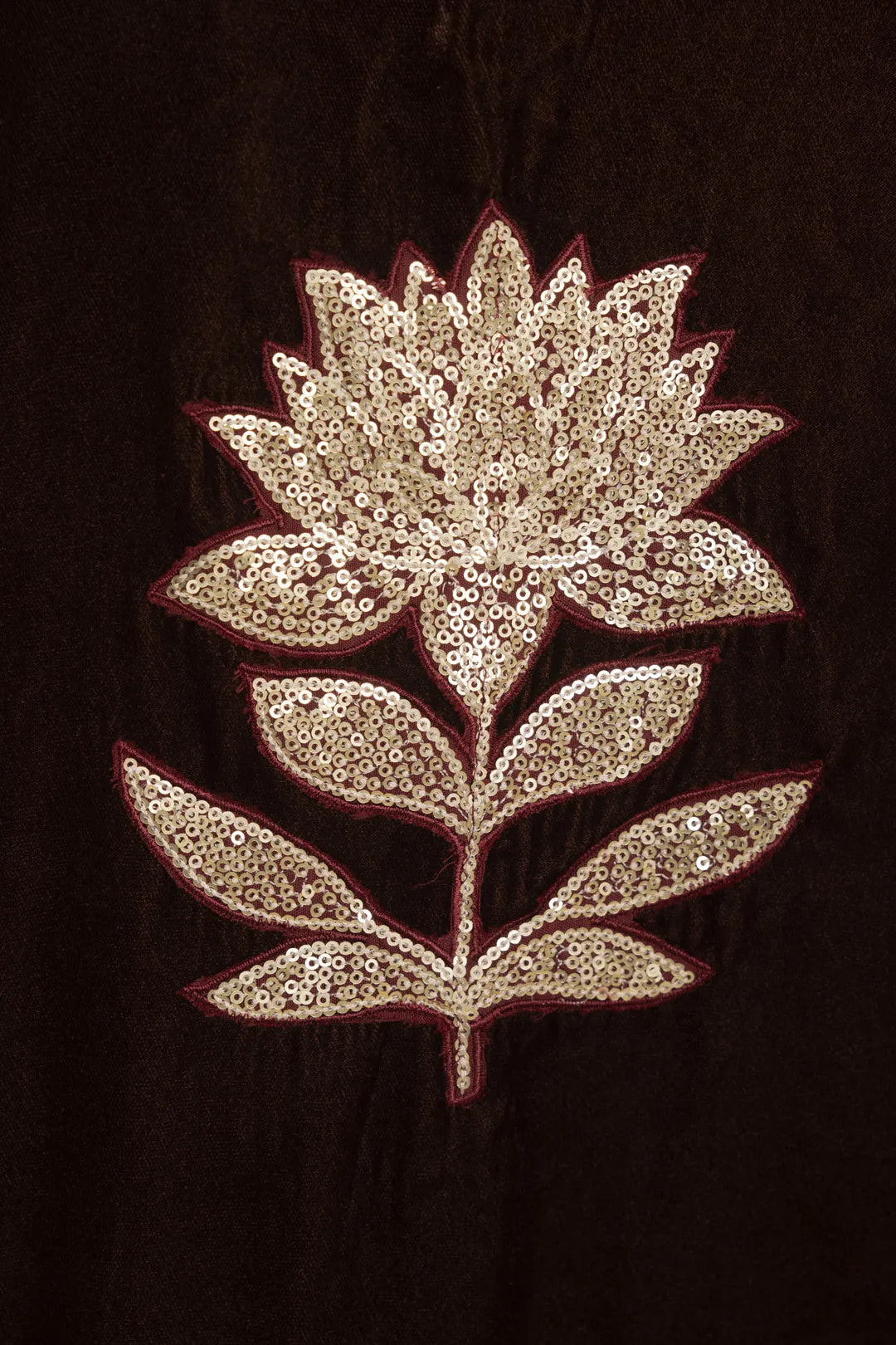 Close-up of gold embroidered floral motif on velvet fabric