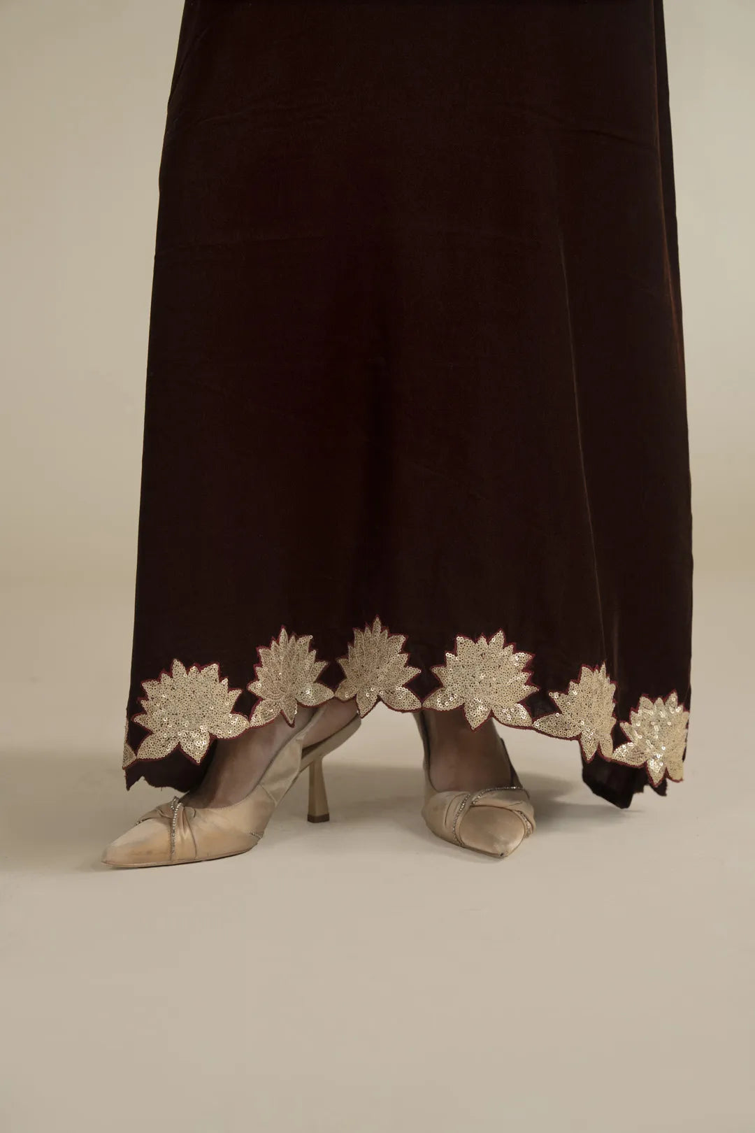Close-up of kaftan hem featuring gold embroidered border detail near the ankles