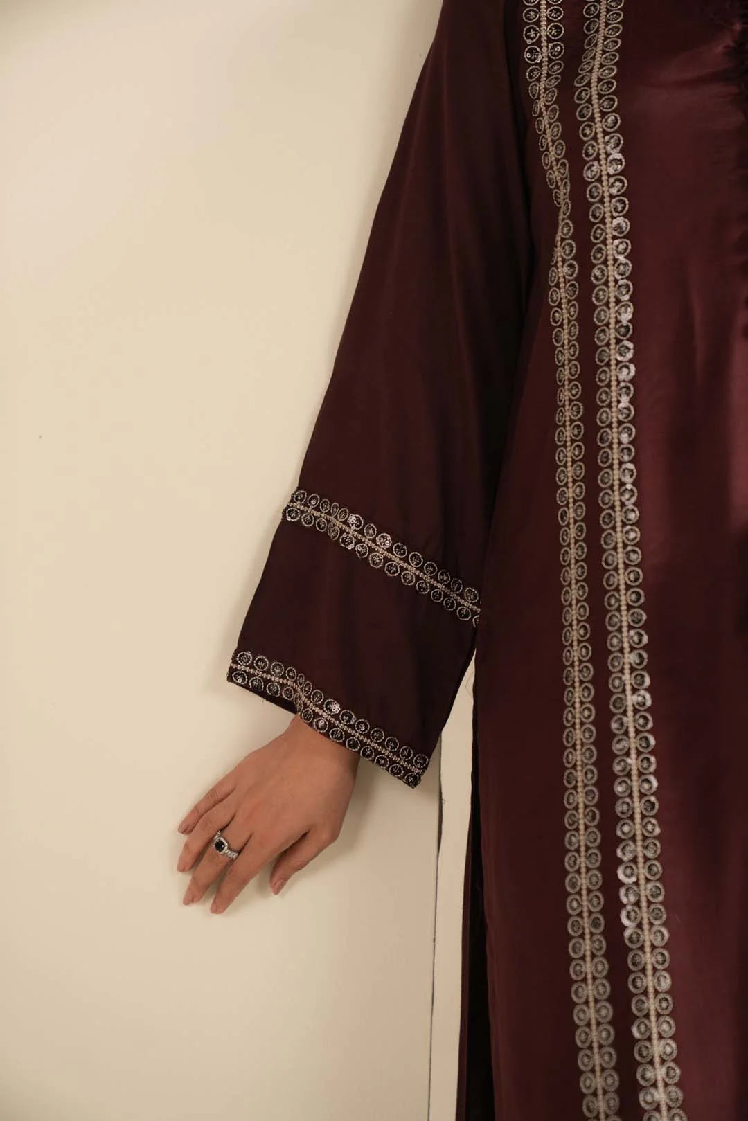 Close-up of maroon suit sleeve showing sequin/trim detailing and fabric texture.