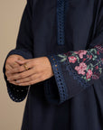Close-up of navy blue suit sleeve showing floral embroidery detail on the cuff area.
