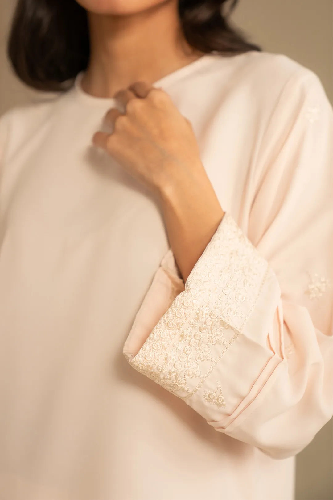Close-up of neckline and upper front of peach embroidered kurta with soft drape.