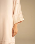 Close-up of peach kurta sleeve showing embroidered cuff detailing.