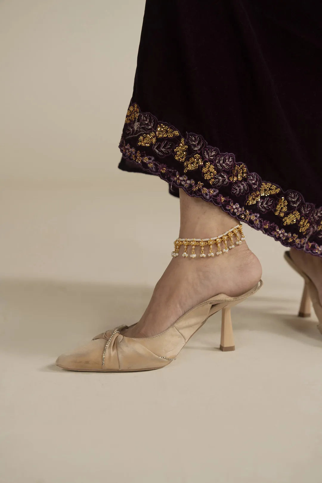 Close-up of velvet kaftan hem showing gold embroidered border detail with model’s shoes