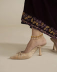 Close-up of velvet kaftan hem showing gold embroidered border detail with model’s shoes