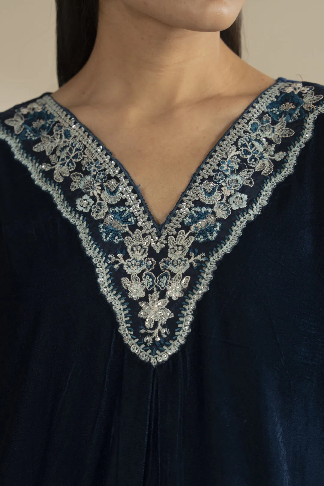 Close-up on the V-neck embroidery showing silver detailing against rich blue velvet.