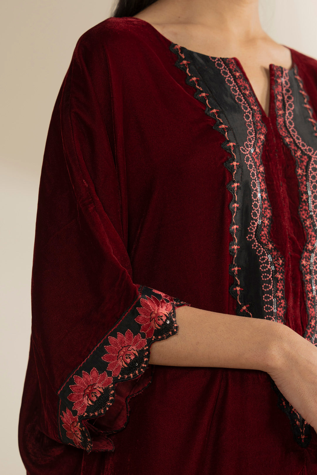 Close-up on the embroidered neckline panel detailing against rich velvet texture.