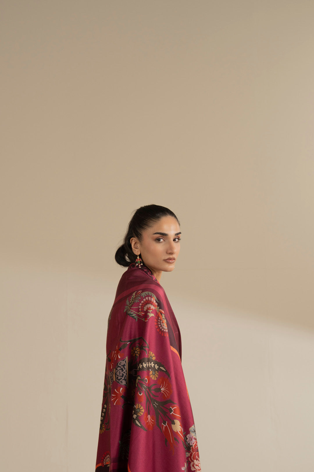 Close-up side portrait of maroon printed winter shawl showing floral motifs and border detail.
