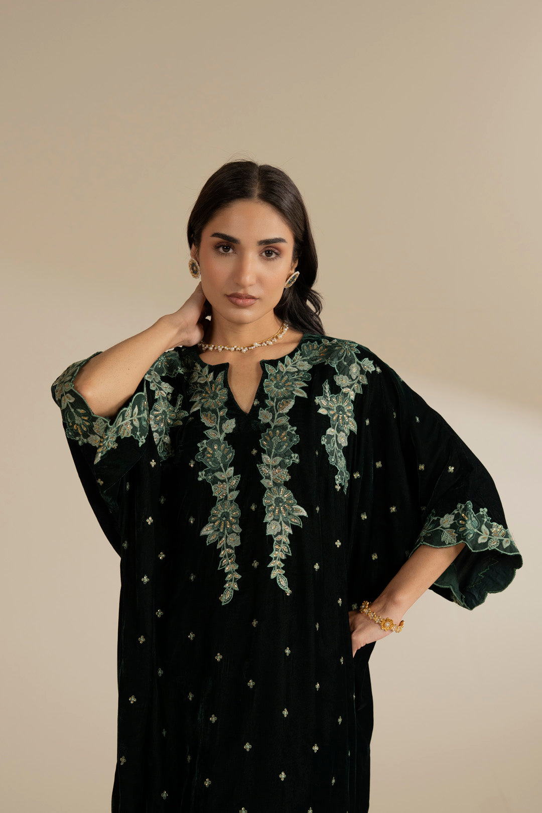 Close-up view of the embroidery detailing on green velvet, highlighting shine and texture.