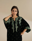 Close-up view of the embroidery detailing on green velvet, highlighting shine and texture.