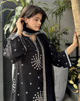 Close framing highlights sequin accents and embroidery on the black raw silk kurta with dupatta drape detail.