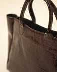 Croc-textured tote bag in shiny brown finish, spacious carryall design photographed from a side-front angle.