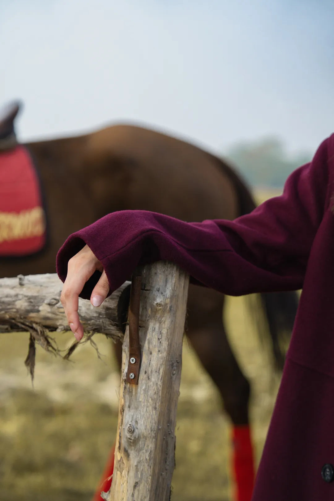 Detail shot of maroon coat sleeve and fabric texture in stretch blend